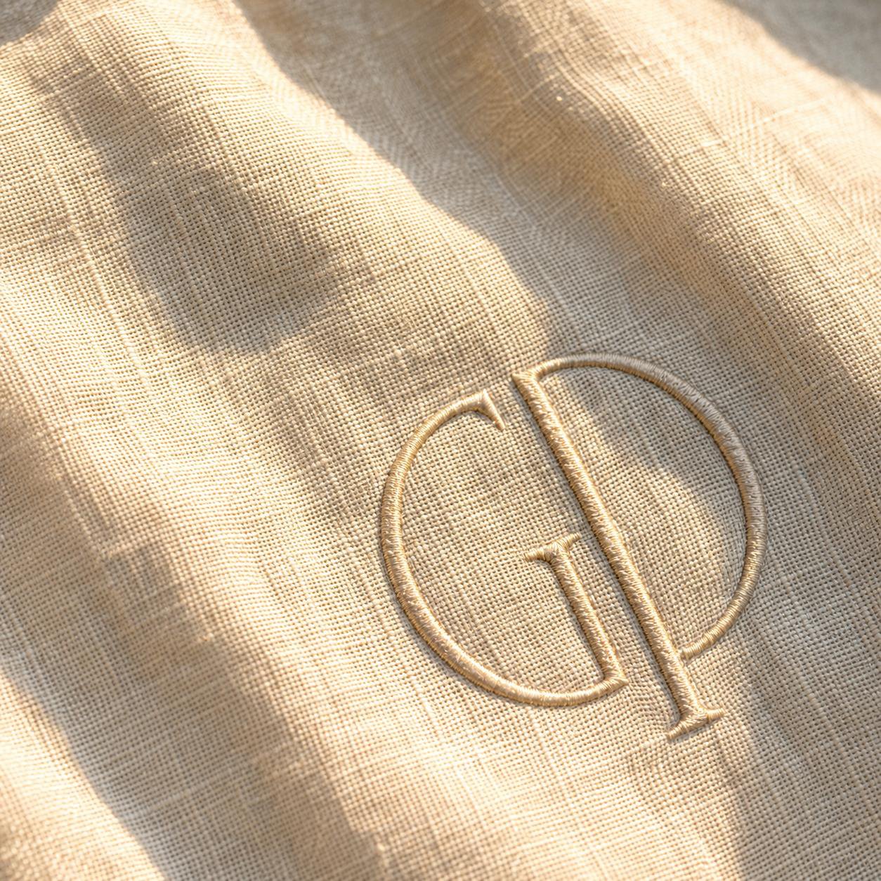 Nahaufnahme des in Champagner-Gold gestickten GP-Monogramms auf Leinen